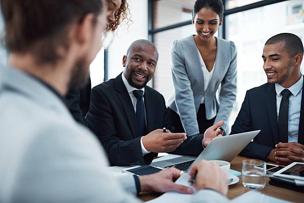 Shot of a group of businesspeople discussing something on a laptop